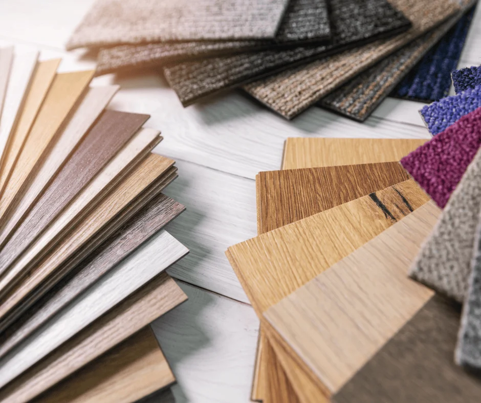 A variety of flooring samples including laminate, vinyl planks, and carpet swatches laid out on a wooden floor